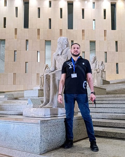 Michael Sabry on the Grand Staircase beside a seated pharaoh statue